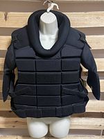 Front view of the black padded chest protector on mannequin with adjustable straps and segmented padding