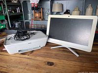 Front view of HP All In One computer and HP printer side by side on wooden table.