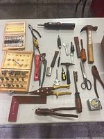 Full lot layout showing hand tools and two router bit boxes spread on a white table.