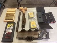 Overview of the woodworking tools laid out on a table showing all items including wooden boxed chisels, mallet, hand plane, saw, black holders, drill bits case, chisel, pliers, and screwdrivers.