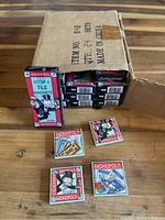 Factory case box with 24 small boxed sets of Monopoly tile magnets. One box is standing upright to show front design and four individual tile magnets are displayed outside the box.