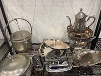The entire collection of vintage silver plated serveware items including teapot on stand, serving trays and covered dishes.