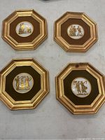 Four octagonal framed wall decor pieces laid out showing classical scenes on ceramic or porcelain plaques