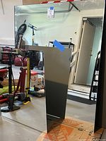 Photo of two mirrors showing reflective surfaces and surrounding garage area, including the beveled mirror and a larger mirror with black frame edges.