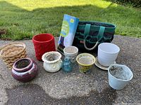 Assorted garden pots and tools displayed on concrete with lawn background