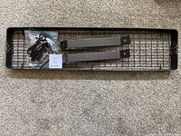 Top view of metal pot rack with accessories including 12 hooks in plastic bag, two metal mounting brackets on a carpeted surface.