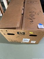 Closed HP cardboard box with exploded-part illustrations and HP logo visible.