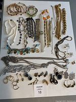 Full lot overview of jewelry items laid out on white background including bangles, bracelets, chain belts, earrings, and necklaces.