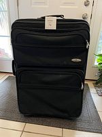 Front exterior view of the luggage showing brand tag 'Atlantic', two large zippered exterior compartments, and retractable handle.