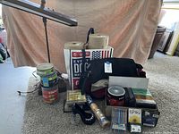 Wide view showing the vintage desk lamp, tape rolls stacked together, pens, messenger bag, multiple blank CDs in tub and jewel cases, cork board roll, and smaller office accessories like a mini stapler and decorative calendar blocks.