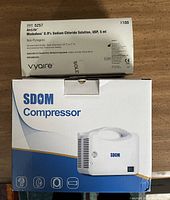 Box of AirLife 0.9% Sodium Chloride Solution 5 ml single-use dose vials by Vyaire and original SDOM Compressor box.