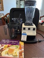 Front view of Vita-Mix blender base with two containers, tamper, stand and recipe books