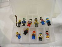 View of all 11 LEGO minifigures in a plastic organizer box showing variety of characters and colors.