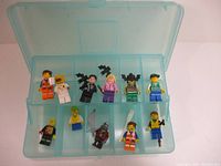 Top-down view of 11 LEGO minifigures in a translucent blue plastic storage case with 10 compartments, showing individual figures and their accessories.