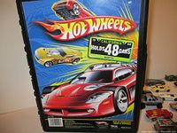 Blue Hot Wheels carrying case showing artwork of red and yellow cars and a label indicating it holds 48 cars.