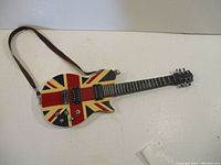 Full view of the decorative guitar showing the U.K. flag design and strap attached.