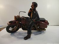 Side view of ceramic man seated on motorcycle figurine, showing detail on the motorcycle and figure.
