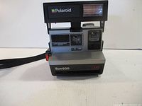 Front view of the Polaroid Sun 600 LMS instant camera showing the flash area with Polaroid branding and front lens section.