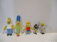 All five Simpsons figurines lined up: Homer, Marge, Bart, and two smaller characters.