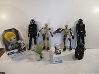 Full lot of seven Star Wars collectables including two black-armored figures, two battle droids, Yoda bobblehead and boxed Luke Skywalker plush toy.