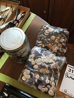 Photo of the two plastic bags filled with assorted vintage buttons and a glass jar containing more buttons, placed on a wooden surface.