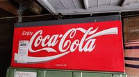 Front of the metal vending machine top with 'Enjoy Coca-Cola' in white script on bright red background.
