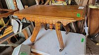 Full view of Eastlake style wooden cottage table with scalloped apron and castor wheels.