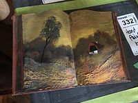 Photo showing the hand painted book sculpture with a tree and cottage in a textured landscape.