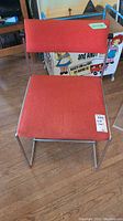 Front view of mid century modern chair with orange fabric and metal frame