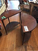 Photo showing set of two MCM demi lune tables on wooden floor, positioned to illustrate shape and height difference.