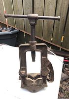 Photo of vintage cast iron pipe vise showing full front with screw handle and serrated gripping jaws.
