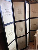 Photo showing three-panel folding screen with wood veneer frames and vintage wine label stamped designs on cream fabric or faux leather panels.
