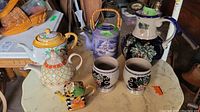 Overview of all items including pitcher, teapots, glasses on a marble surface