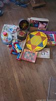 Photo showing assortment of vintage toys including Barrel of Monkeys, wooden Marionette, plastic tea cups, Freeze Frame game, Chinese Checkers board, wire puzzles, and cookie cutters.