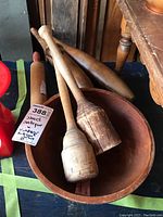 Wooden bowl filled with two vintage pestles and showing part of a juggling pin