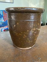 Front view of 1800s redware crock showing rounded rim, incised line, and brown speckled glaze.