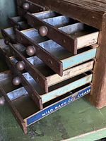 Side angled view showing drawer open to reveal tin lining and painted drawer fronts, including one labeled drawer.