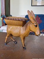 Front-left side view of the vintage plastic donkey dispenser showing the textured fur and hinged top compartment.