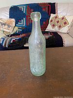 Front view of the antique aqua blob top glass bottle showing overall bottle shape and aqua coloration.