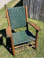 Full view of antique armchair showing wood frame and woven green splint seat and backrest.