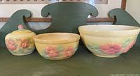 Three-piece set of antique Hull pottery including two nesting bowls and one jar with lid on green shelf