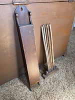 Antique wooden match safe box and wooden drying rack side by side on a rusty metal surface indoors