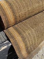 Close-up image of rolled carpet showing dense woven jute fibers with brown and tan stripes.