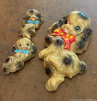 Top view of three chalkware puppies with painted bows on a wooden surface