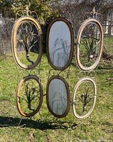 Front side of the metal room divider with six oval panels, featuring two panels with bird artwork and four with decorative metalwork.