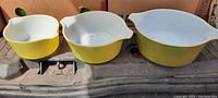 Three yellow Pyrex mixing bowls nested inside each other, showing full set and size difference.