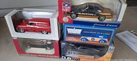 Photo showing the Budweiser red panel truck, NFL Ravens car, and other die cast collectible vehicles in packaging