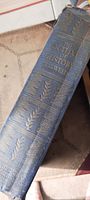 Spine of the book showing title 'The Outline of History H.G. Wells' embossed in gold on dark blue cloth with decorative leaf patterns.
