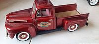 Side view of maroon die cast 1950 Ford pickup toy showing door decal, whitewall tires and truck bed detail