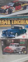 Three stacked sealed car model kit boxes showing a 1948 Lincoln Continental, Havoline Ford Thunderbird race car, and 56 Ford F-100 truck.